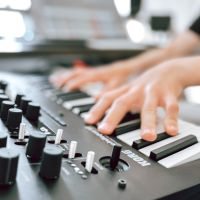 Bild på händer som spelar på en synth