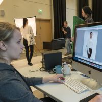 En tjej sitter framför en dator och gör fotoredigering