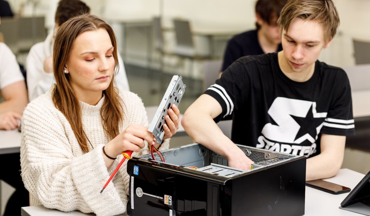 Några studerande demonterar en dator i ett klassrum