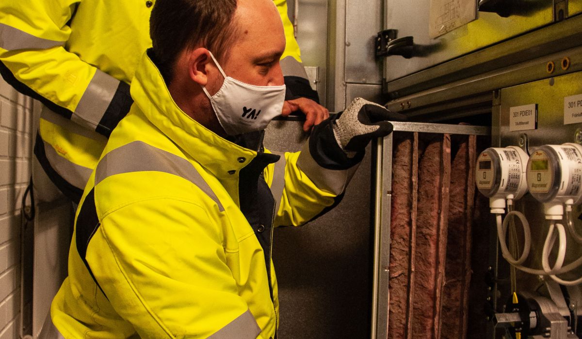 ett par fastighetsskötare ser på ventilationssystemet i en fastighet