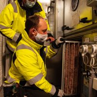 ett par fastighetsskötare ser på ventilationssystemet i en fastighet